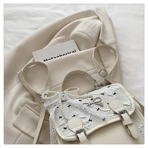 Détail d'un sac à dos Lolita crème avec dentelle, chaîne de perles et fermoir nœud en métal