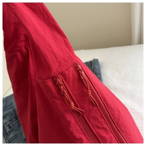 Detail of red tote bag featuring parallel zippers and matching woven cord pullers