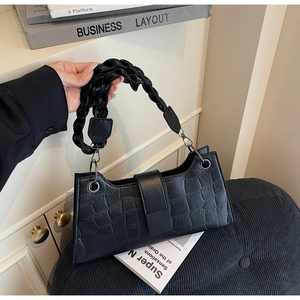 Detail of black crocodile texture bag with distinctive woven pleated handle and buckle
