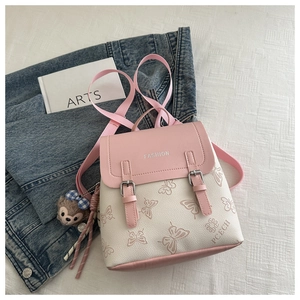 Detail of pink leather flap and butterfly pattern backpack with a plush bear charm