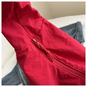 Close-up of bright red nylon jacket featuring a zipper with a matching woven pull cord