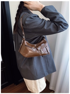 Detail shot of vintage brown glossy leather underarm bag with silver buckle and zippers