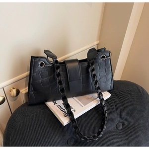 Detail of black faux crocodile leather bag with unique twisted woven shoulder straps