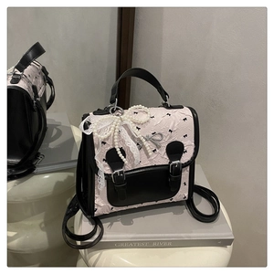 Détail du sac à dos rose à fleurs avec finitions en cuir noir et breloque en dentelle