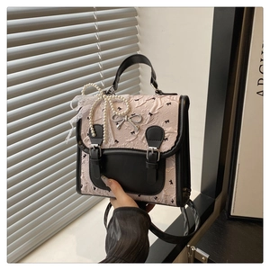 Vue détaillée du tissu jacquard rose avec garniture en cuir noir et breloque noeud en perles