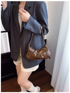 Detail of a brown crescent shoulder bag in sleek faux leather with silver buckle and side zipper