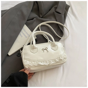 Dettaglio borsa Boston crema con fibbia a fiocco argento e pizzo a forma di cuore