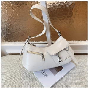 Detail of cream white faux leather shoulder bag with silver buckles on a magazine