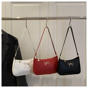 Close-up of bow decor and flower pendant on white, red, and black baguette bags