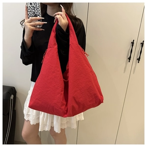 Detail of red large capacity tote bag with drawstring side and crinkled texture fabric