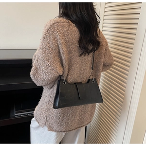 Close-up of black crocodile embossed shoulder bag with slim strap and metal ring detail