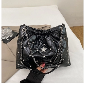 Detail of black quilted tote bag with silver studs and rhinestone star decoration