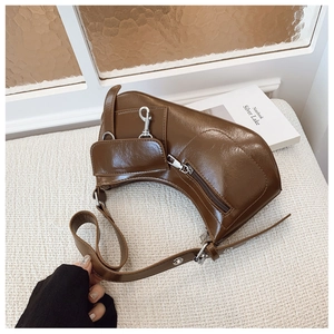 Detail of dark brown oil wax leather crescent bag with silver zippers and side pocket