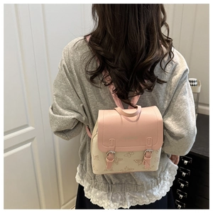 Mini pink and beige backpack with butterfly pattern shown worn on a model's back