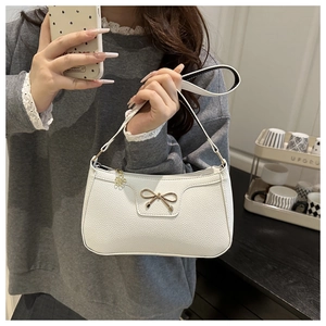 Close-up of white lychee pattern leather shoulder bag with golden bow hardware detail