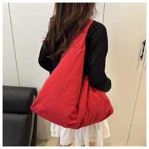 Back view of a model wearing a large red casual tote bag made of textured nylon fabric