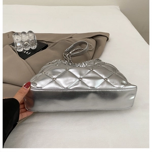 Close-up of silver quilted tote bag with rhinestone details and metallic chain strap