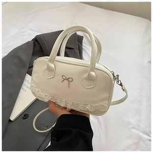 Dettaglio della borsa Boston crema con fiocco argento e finiture in pizzo eleganti