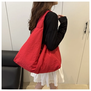 Model showcasing a large red nylon tote bag with a minimalist curved design for daily commute