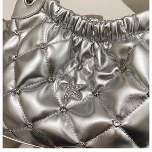 Close-up of silver quilted tote bag with star metal emblem and rhinestone details