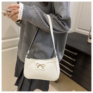 Close-up of white PU leather shoulder bag with lychee texture and golden bow detail