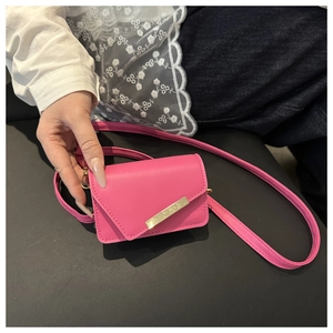 Close-up of pink mini crossbody bag with gold metal buckle held by a model