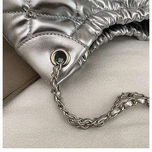 Detail of silver metallic quilted tote with chain strap and drawstring design