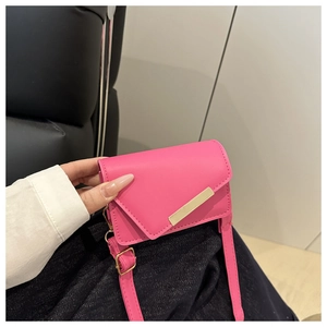 Detailed view of fuchsia mini flap bag with gold metal trim held in hand for size comparison