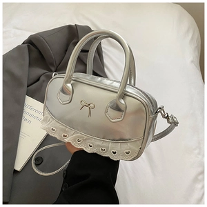 Dettaglio della borsa Boston argento con fiocco in metallo e bordo in pizzo bianco