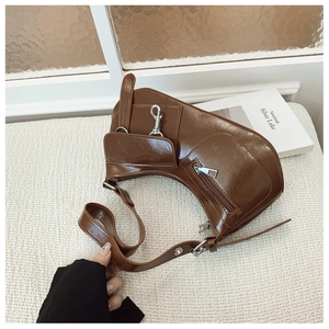 Detail of glossy brown crescent bag with silver hardware and adjustable shoulder strap