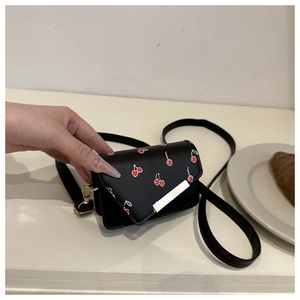 Miniature black crossbody bag with red cherry prints and golden metal buckle details