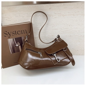 Detail of a brown glossy leather half-moon bag with retro industrial metal hardware