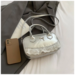 Dettaglio della borsa Boston argento con fiocco in metallo e bordo in pizzo cuore