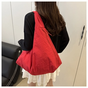 Model wearing a large red nylon tote bag featuring a semi-moon shape and side view details