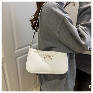 Close-up of white lychee pattern faux leather bag with golden metal bow buckle