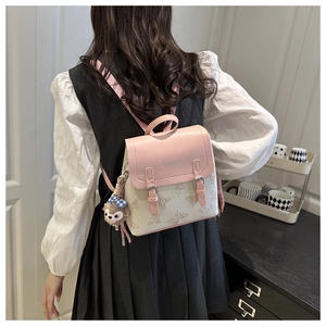 Detailed shot of pink and beige faux leather mini backpack with butterfly print and plush charm