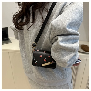 Detail of black cherry print crossbody bag showing gold metal trim and adjustable strap