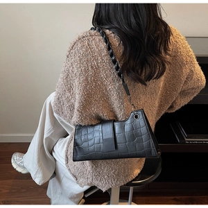 Detail of black crocodile texture baguette bag with thick braided rope shoulder strap