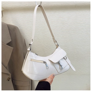 Detailed view of white crescent shoulder bag with silver buckles and decorative pockets