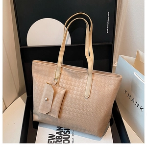 Detail view of beige houndstooth embossed tote bag with matching hanging coin purse accessory