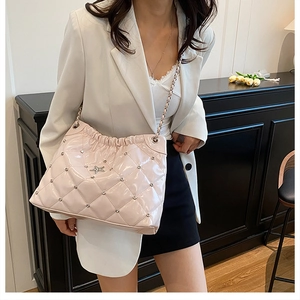Detail of light pink quilted leather bag featuring star logo and chain strap
