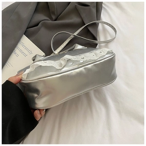 Dettaglio del pizzo bianco su una borsa Boston argento metallizzato in ecopelle