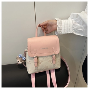Detail of pink and beige mini backpack with butterfly print and plush bear pendant