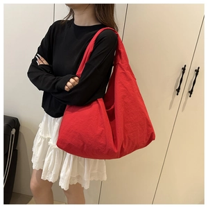 Detailed view of a large red nylon hobo bag carried by a model for a casual daily look