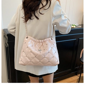 Detail of light pink quilted patent leather bucket bag with star rhinestone emblem