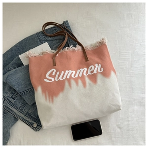 Detail of pink tie-dye canvas tote bag with fringed edges and Summer lettering