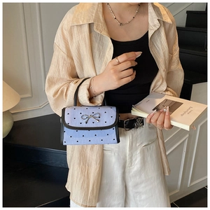 Detail of light blue crossbody bag with heart print, bow clasp and black top handle