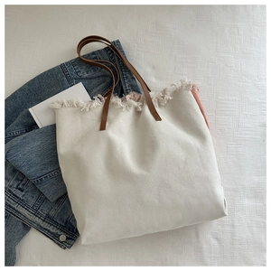 Detailed top view of large canvas beach tote bag with fringe trim and brown leather straps