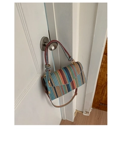 Close-up of colorful striped woven crossbody bag with knotted handle detail on door