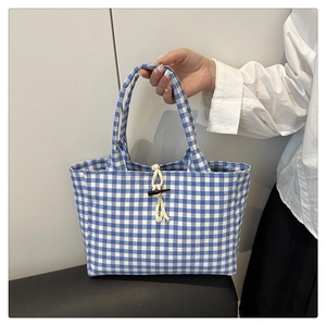 Dettaglio della borsa tote a quadri blu con chiusura a alamaro e manico a treccia